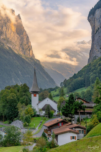 Lauterbrunnen church at sunset with the gold light touching the mountains in the background