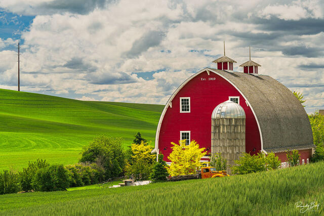 orange truck next to a red barn near Colfax Washington